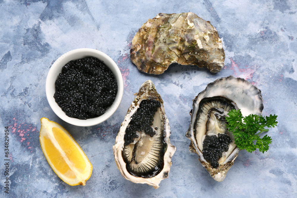 Tasty oysters with lemon and black caviar on blue background