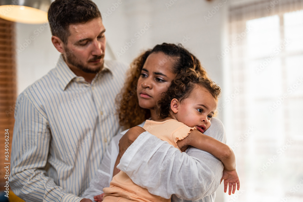 African American mother tosses young baby girl up in living room at home. 