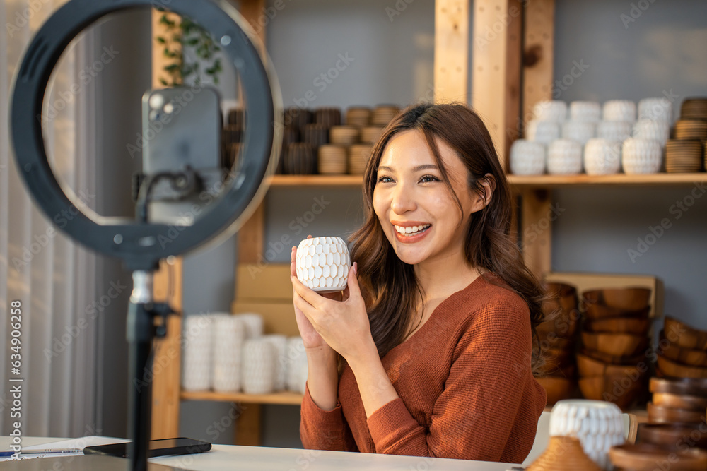 Asian young woman selling vase product online live streaming at home. 