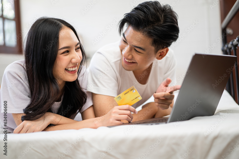 Asian attractive woman using laptop on bed with husband in the morning. 