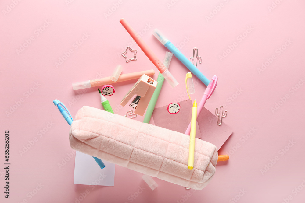 Pencil case and stationery flying on pink background