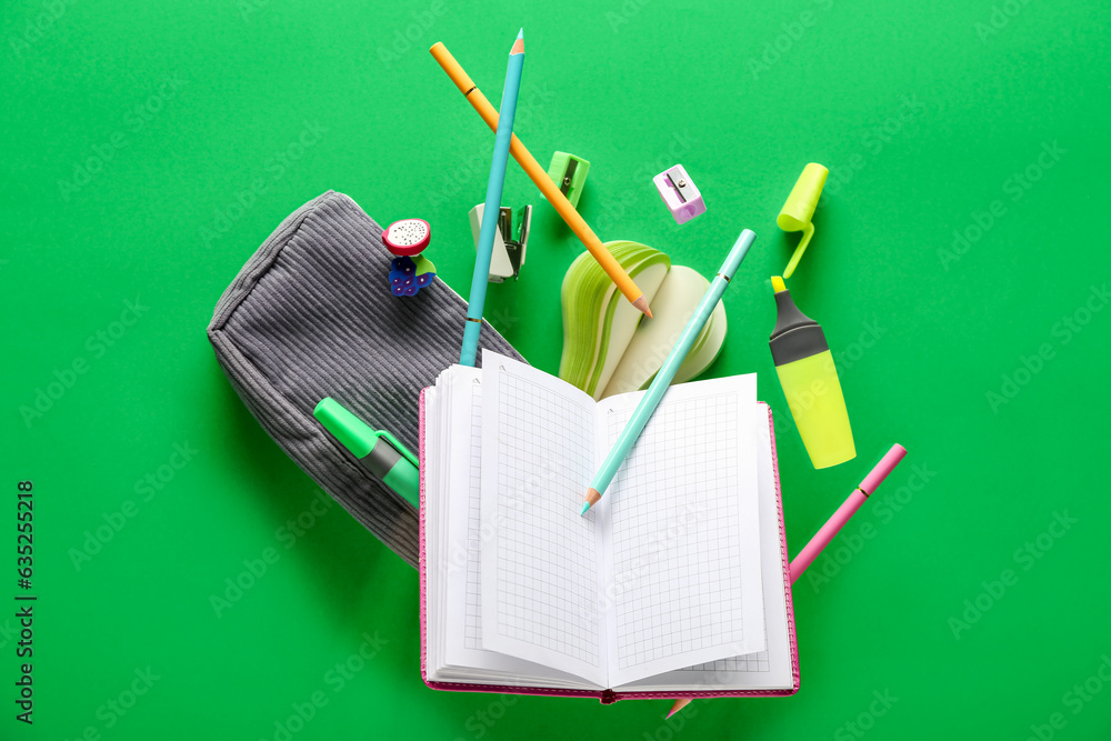 Different stationery flying on green background