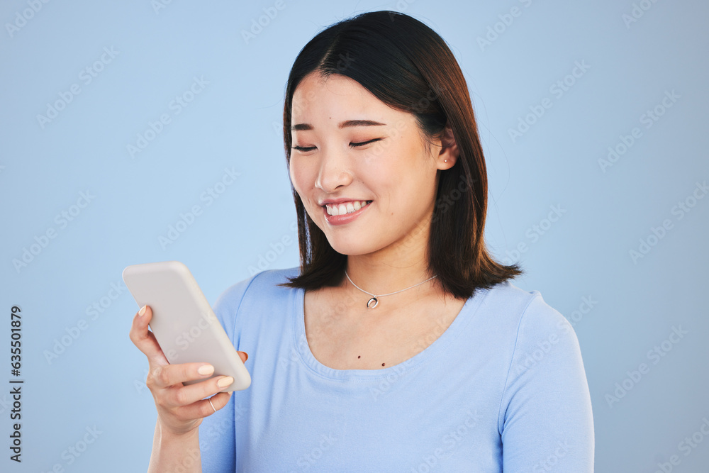 Happy asian woman, phone and typing in social media, networking or communication against a blue stud