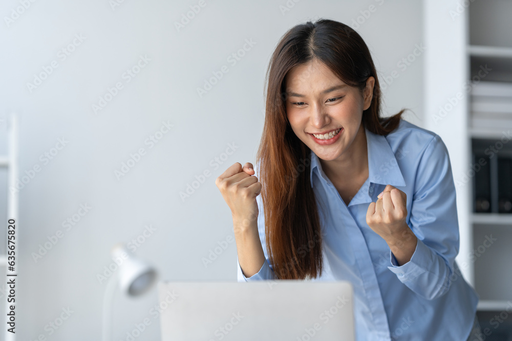 Happy Asian businesswoman standing at her desk in office Received information from laptop computer o