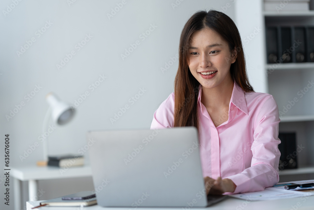 Beautiful asian businesswoman working on laptop and calculating with financial calculator from stati