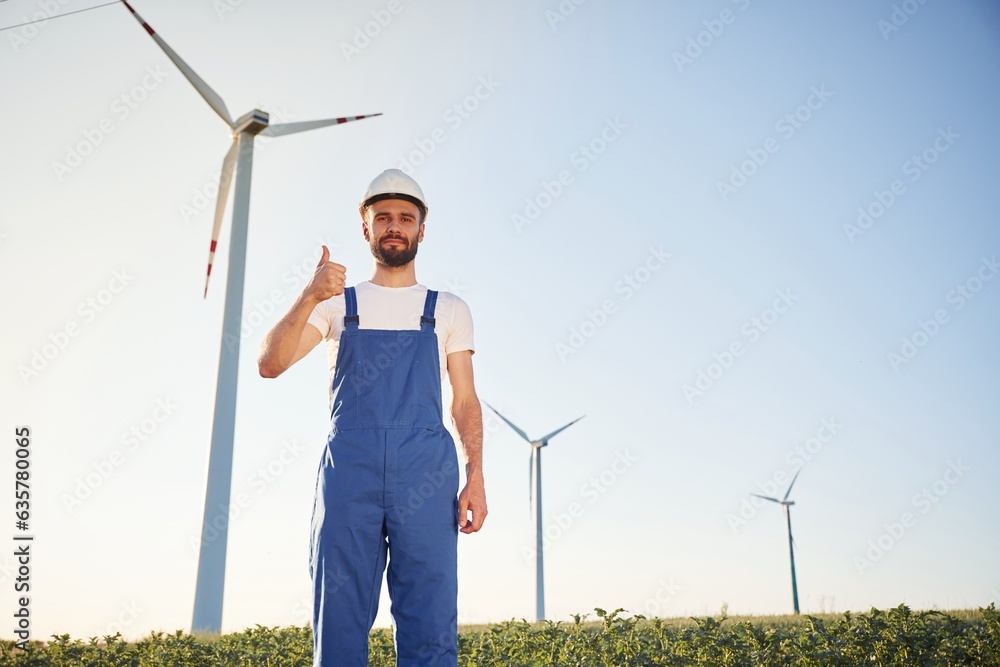 Positive service engineer is on the field with windmills