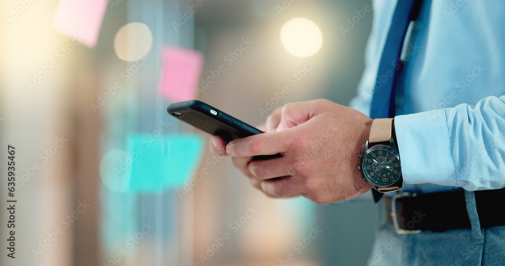 Businessman texting an email on his phone in a modern office. Corporate worker schedule a meeting wi