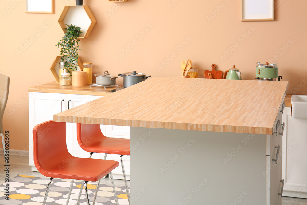 Interior of modern kitchen with bar stools near table