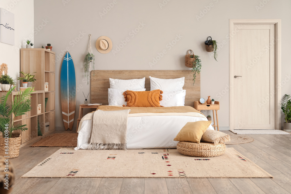 Interior of light bedroom with surfboard, houseplants and shelving unit