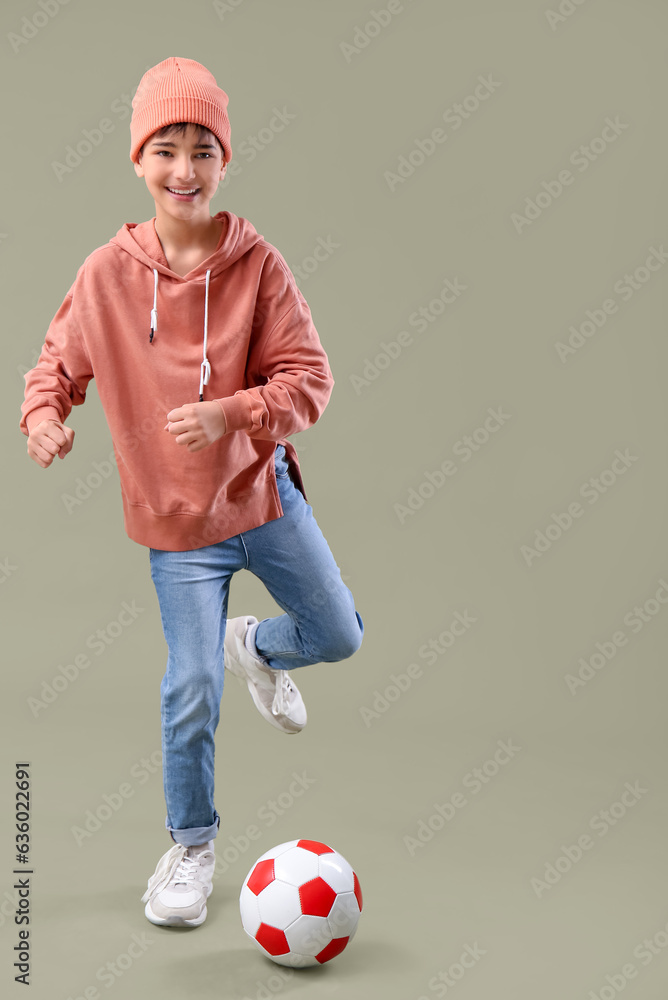 Little boy playing with soccer ball on color background