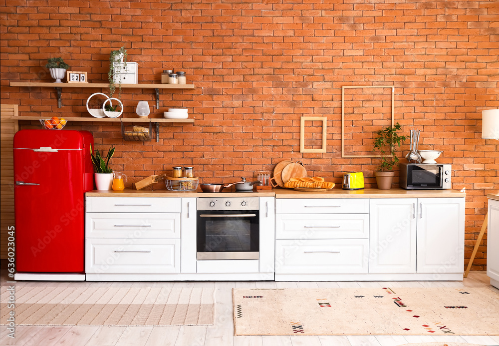 Interior of stylish kitchen with red fridge, counters and shelves