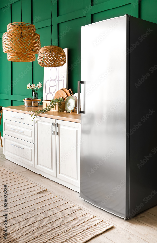 Interior of kitchen with stylish fridge, counters, lamps and picture