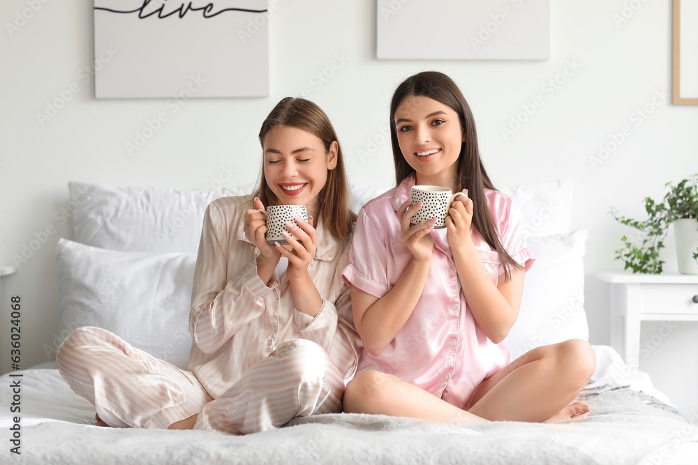 Female friends drinking coffee in bedroom