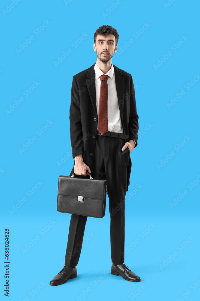 Young man in suit with briefcase on blue background