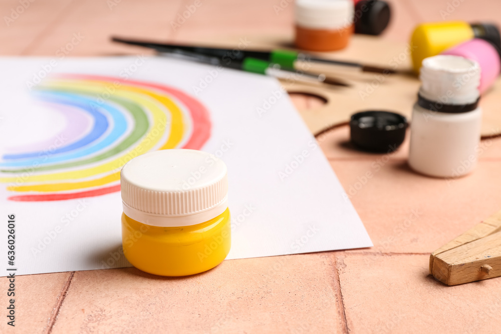 Drawing of colorful rainbow and  paints on beige tile background