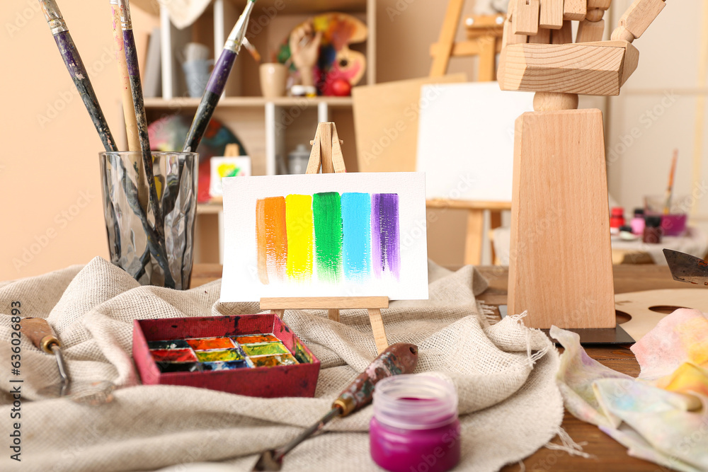 Glass with brushes, paints and mini easel in artists studio