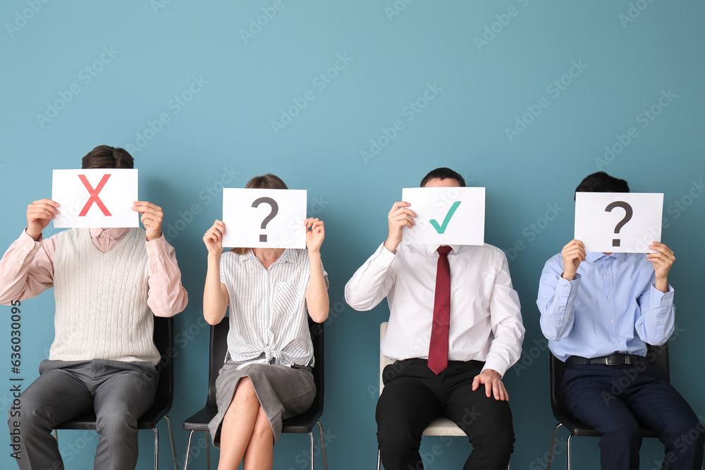 Young applicants holding paper sheets with different marks in room