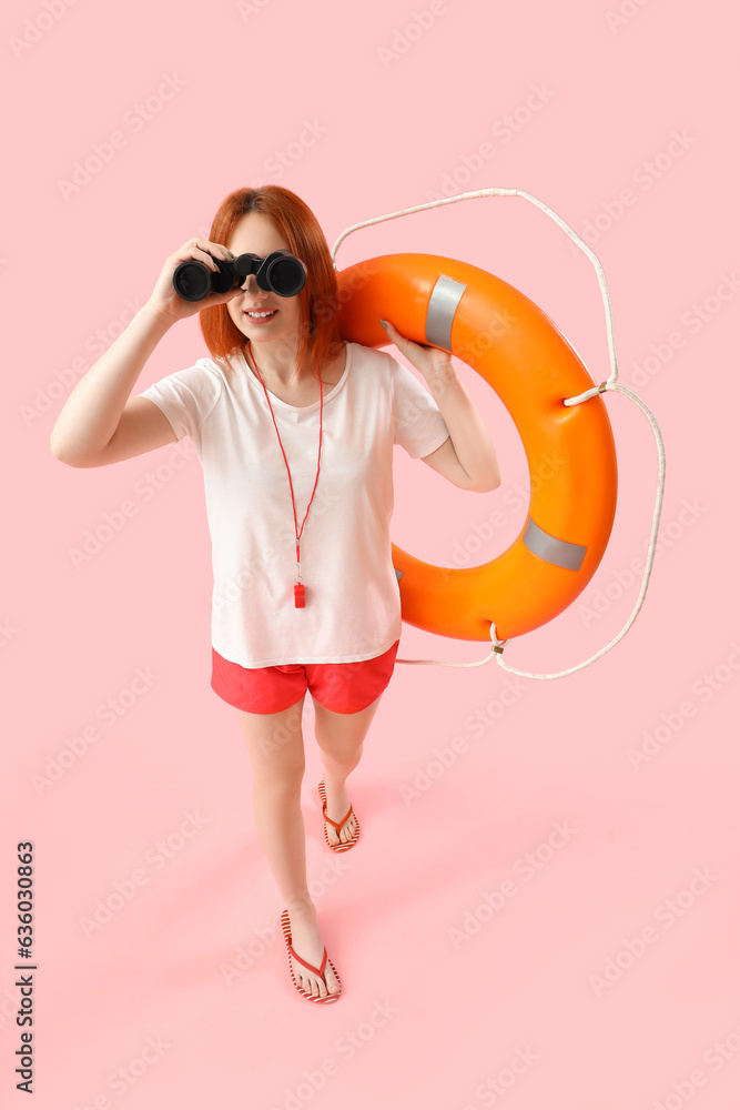 Female lifeguard with ring buoy and binoculars on pink background