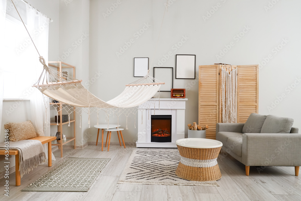 Interior of light living room with fireplace and hammock