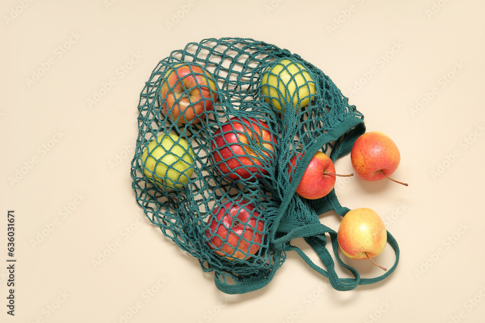 Mesh bag with fresh apples on beige background