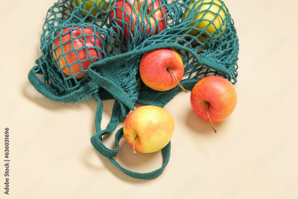 Mesh bag with fresh apples on beige background, closeup