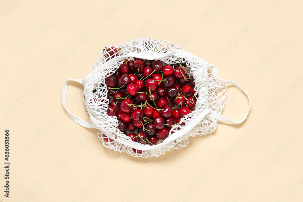 Mesh bag with fresh cherry on beige background