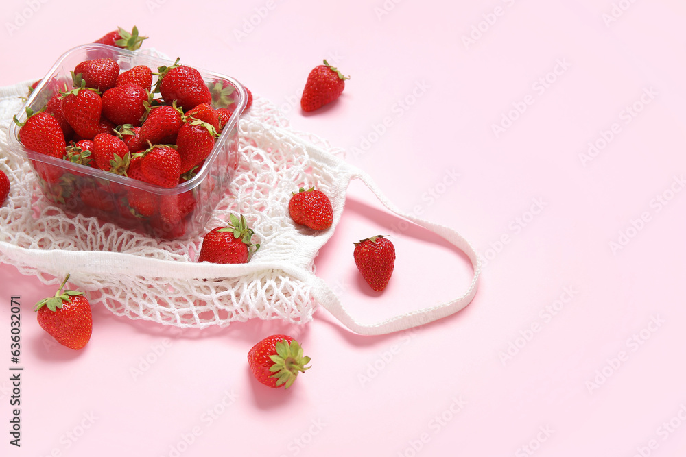 Mesh bag with fresh strawberry in plastic container on pink background, closeup