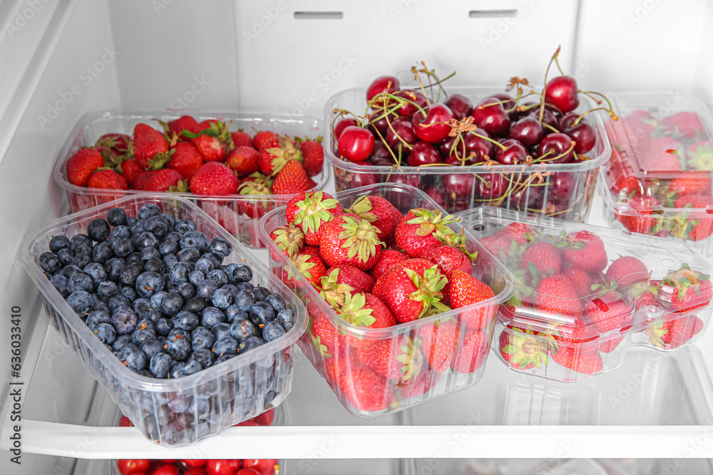 Plastic containers with fresh berries in refrigerator