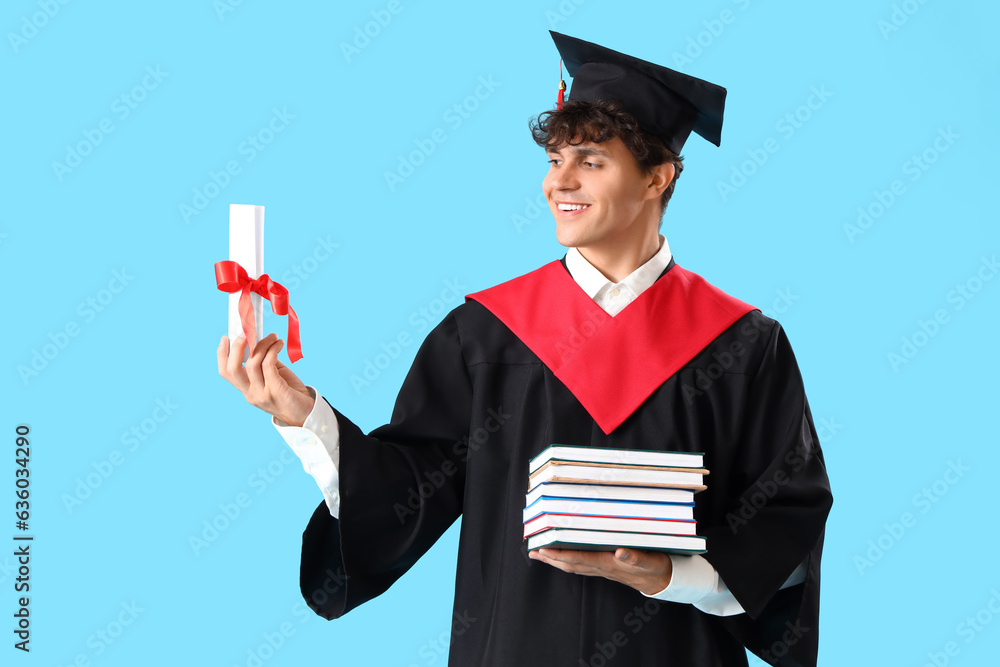 Male graduate student with diploma and books on blue background