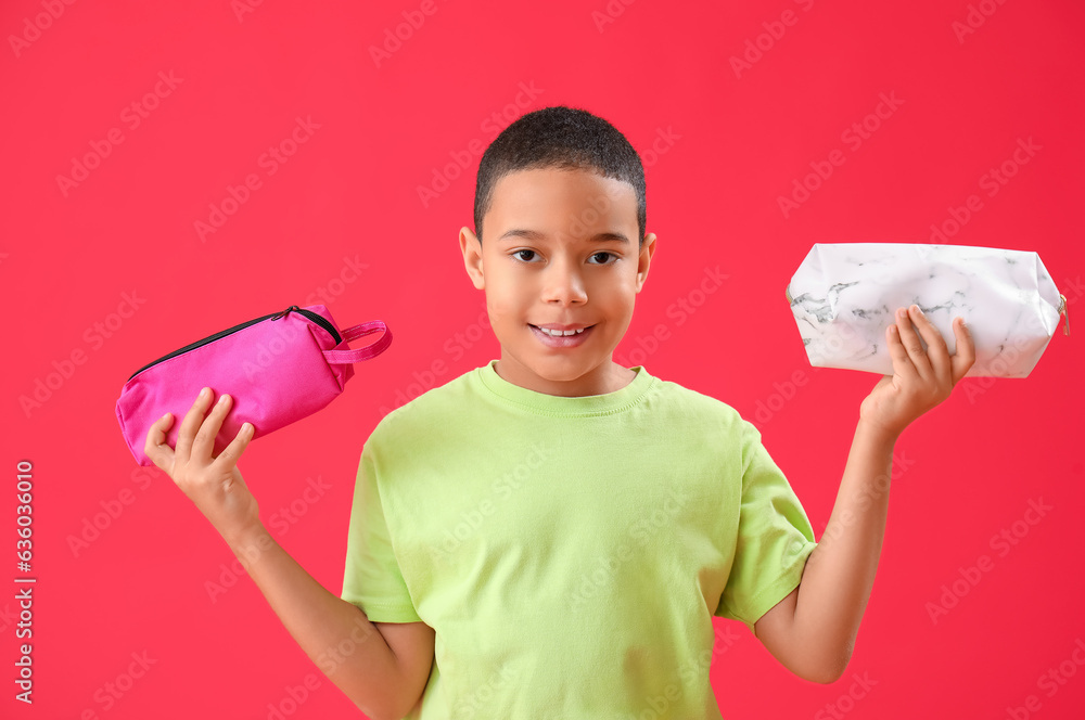 Little African-American boy with pencil cases on red background