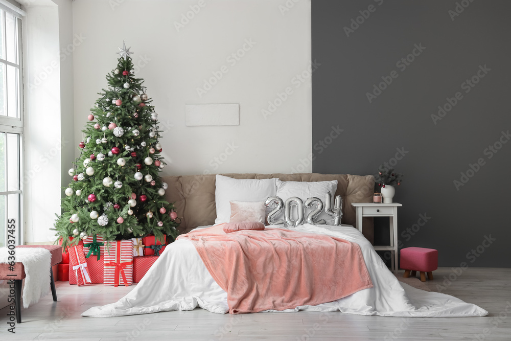 Balloons in shape of figure 2024 on comfortable bed in bedroom with Christmas decor