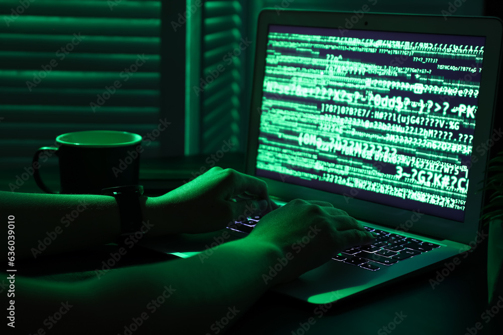 Female programmer typing on laptop keyboard at night in office, closeup