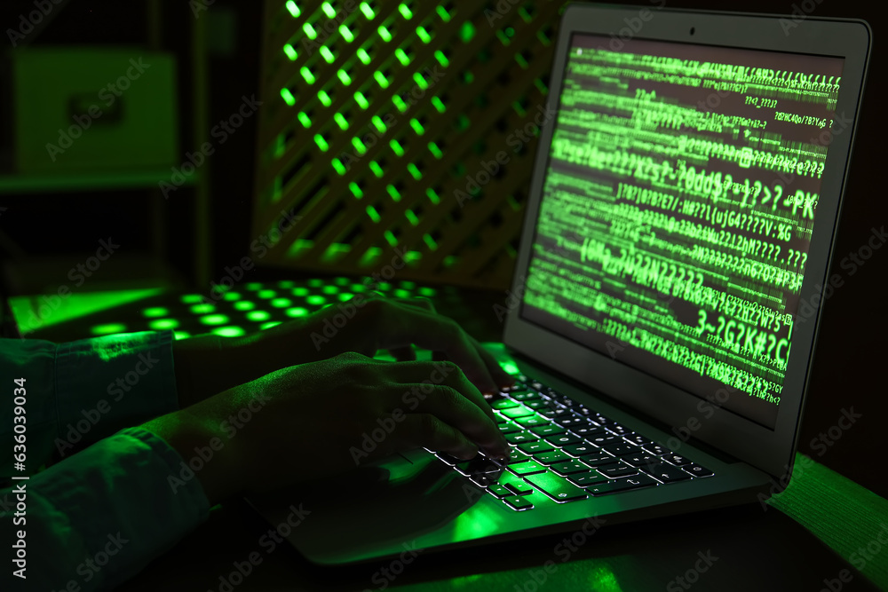 Female programmer typing on laptop keyboard at night in office, closeup