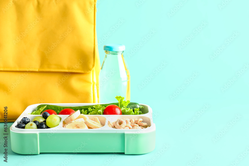 Bag, bottle of water and lunchbox with tasty food on turquoise background