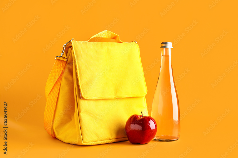 Lunch box bag with apple and bottle of water on orange background