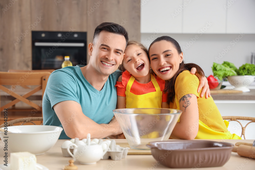 Happy parents with their little daughter preparing dough in kitchen