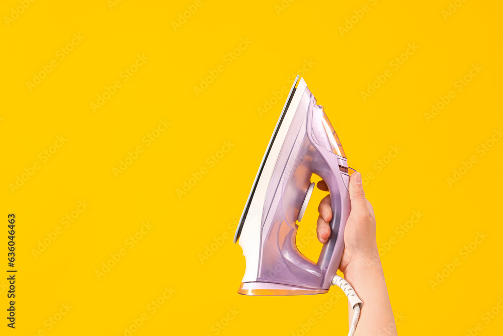 Woman with iron on yellow background