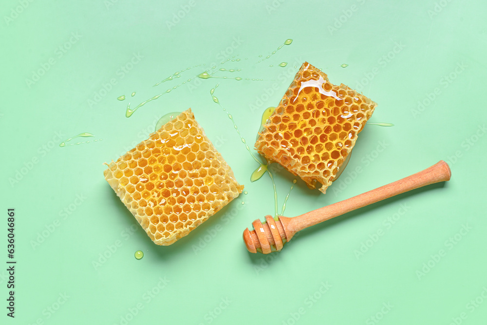 Sweet honeycombs and dipper on green background