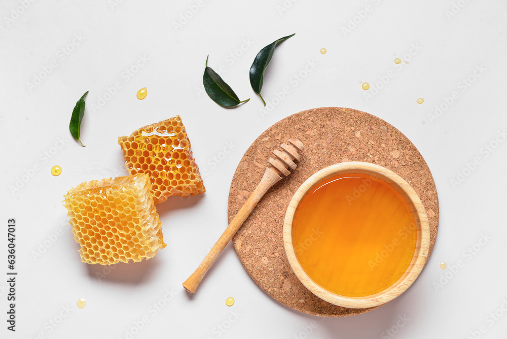 Bowl with sweet honey and combs on grey background