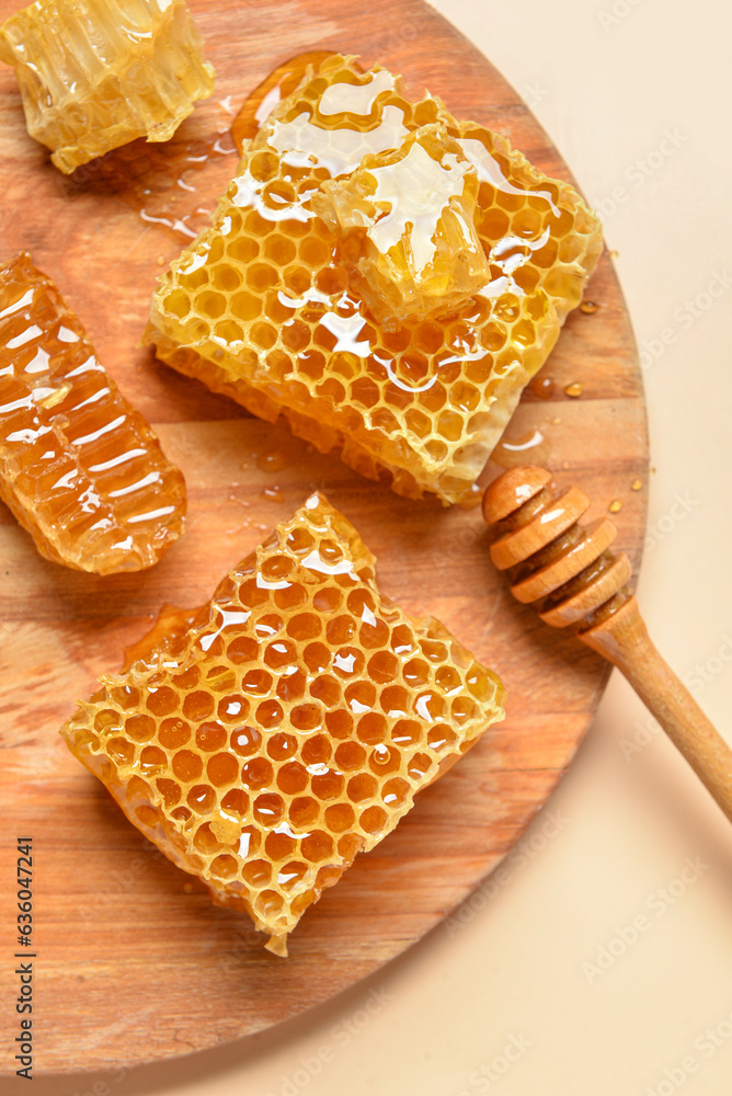 Wooden board with sweet honeycombs and dipper on yellow background