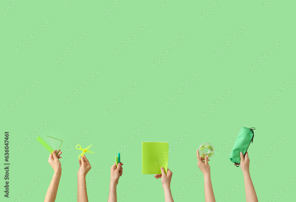 Hands holding school supplies on green background