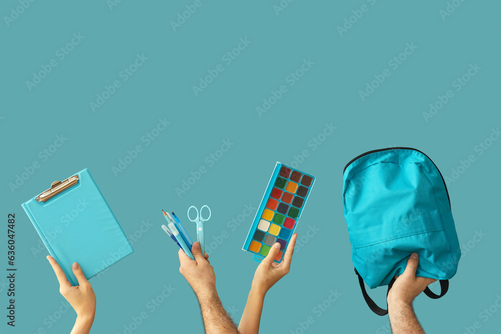 Hands holding school supplies on blue background