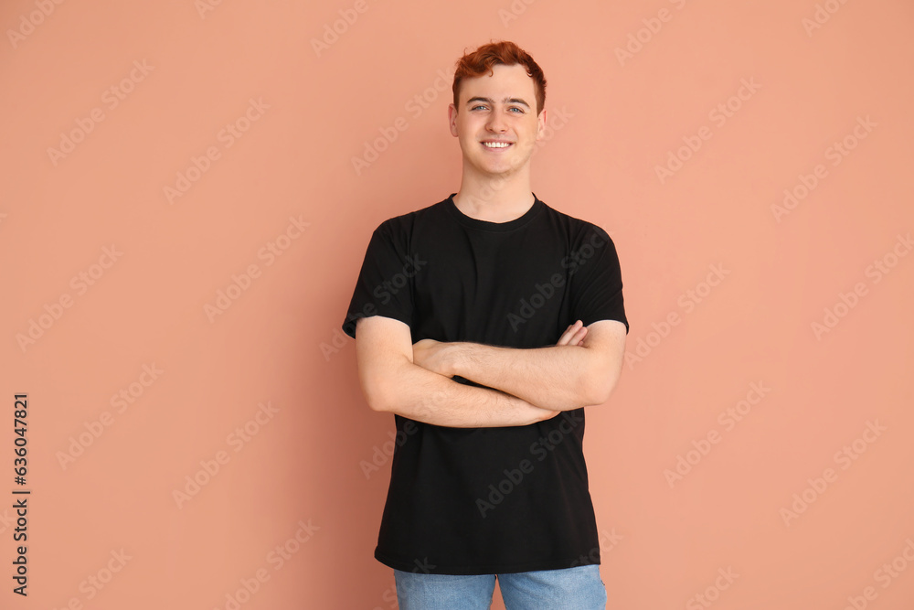 Young man in black t-shirt and with crossed arms on beige background