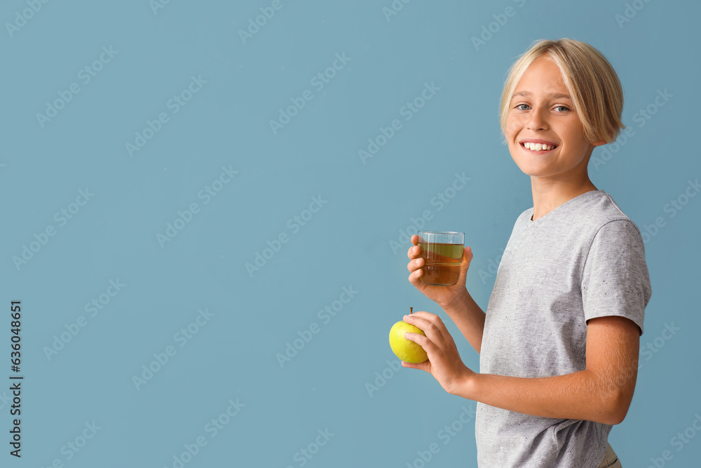 Little boy with glass of juice and apple on blue background