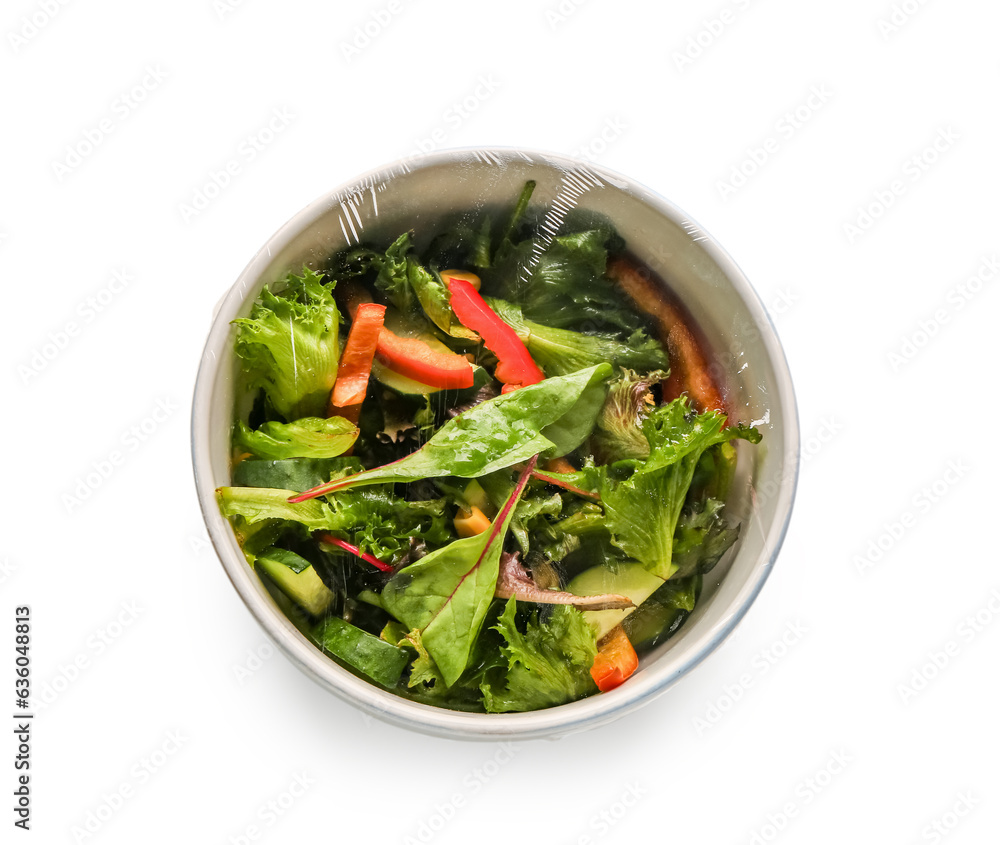 Bowl of fresh salad covered with plastic food wrap on white background