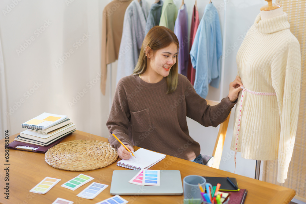 Fashion design concept, Fashion designer measuring sweater in mannequin and taking notes to checkup