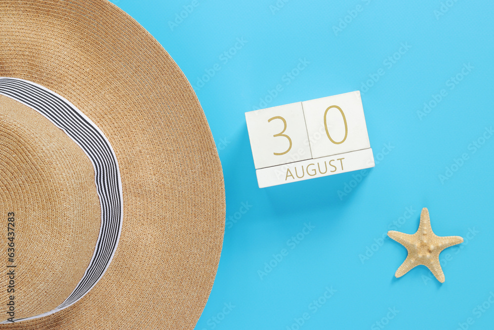 30, August. Wooden calendar on a blue background with summer accessories, top view. Vacation in summ