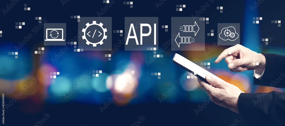 API - application programming interface concept with businessman using a tablet computer at night