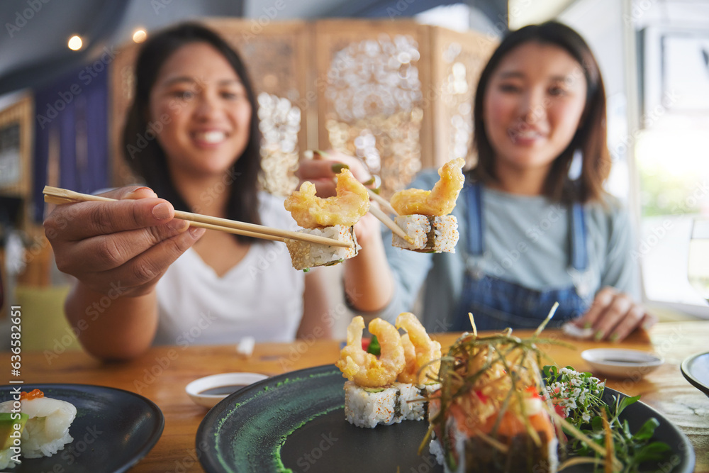 Chopsticks, girl friends and shrimp sushi at a table with salmon and Japanese cuisine food at restau