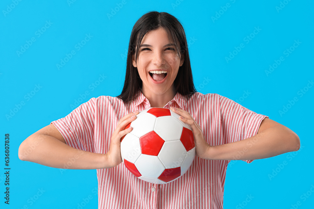 Happy young woman with soccer ball on blue background